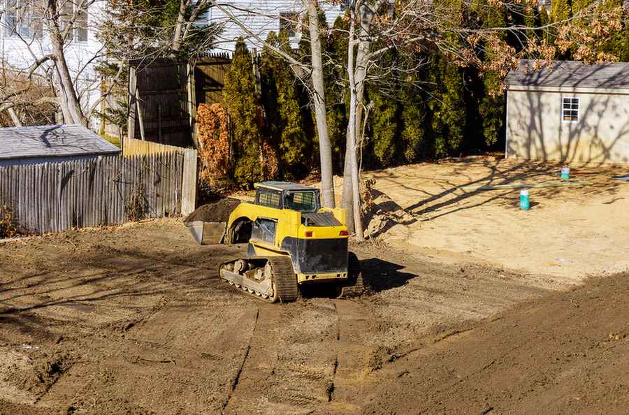 Bulldozer grading land near fence